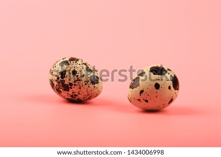 two quail eggs on a pink background