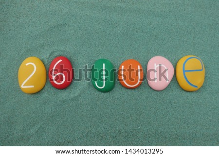 26 June, calendar date composed with multi colored stones over green sand