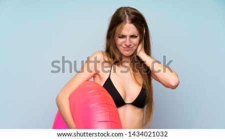 Young woman in bikini in summer holidays covering both ears with hands