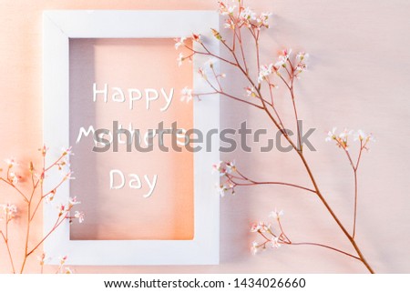 White wooden frame on a coral textured background with small flowers and the inscription Happy Mother's Day - greeting card