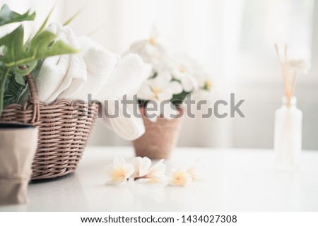 White table, body care products and towel. Bath preparation. White interior of bathroom