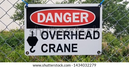 A Danger Overhead Crane Sign on a wire fence.