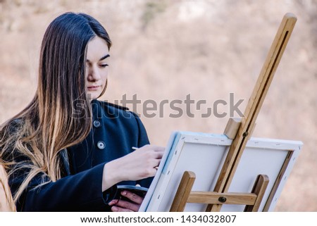 Happy girl painting a picture with 
 water colors outside 