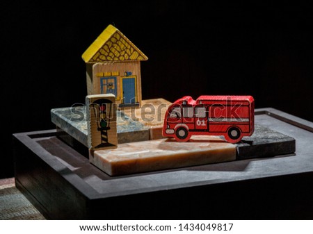 the toy scene is on the stone tiles there are wooden toys: a red fire truck, a traffic light, a house