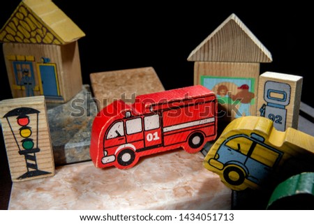 the toy scene is on the stone tiles there are wooden toys: a red fire truck, a traffic light, a house