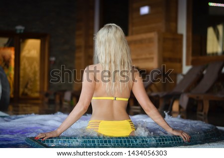 Young caucasian blonde girl relaxing  in jacuzzi hot tub  durig  winter vacation  holiday 