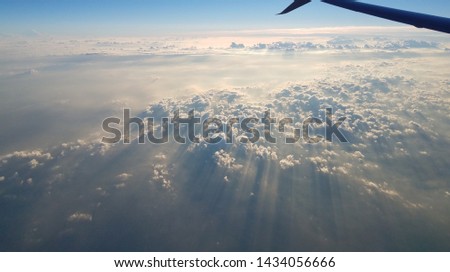 Beautiful sun rays streaming through the clouds in this amazing view from above.  Above the clouds flying above, this image was captured from the airplane window.