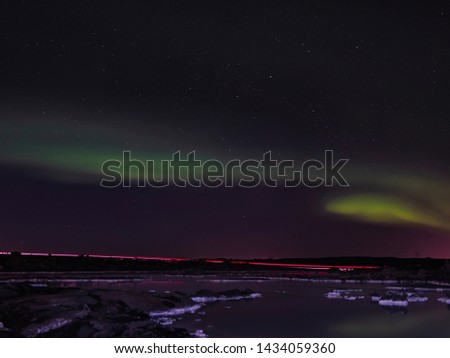 A trail of lights from a car and the northern lights over the Blue Lagoon in island