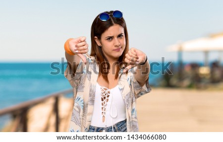 Young woman in bikini in summer holidays showing thumb down at the beach