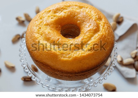 Tangerine and nuts cake on light gray background with nuts scattered. Morning light and clean scene.