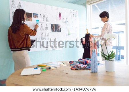 Rear view of beautiful diverse female fashion designers working in a modern office