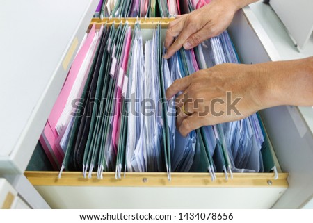 Hand of Man Search files document in a file cabinet in work office, concept business office life.