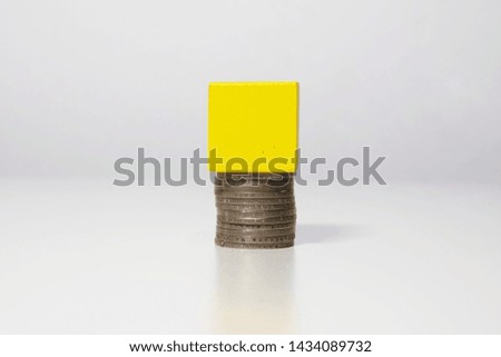 High key picture of wood building block with coins under it. It is the best time to invest in property and asset.