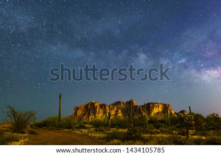 The Milky Way rises over the iconic Superstition Mountains east of Phoenix in the clear desert sky in this Arizona wilderness area. Cactus complete this desert night landscape image with sky stars