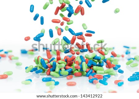 Many different red, blue and green pills falling on the table, isolated on  white