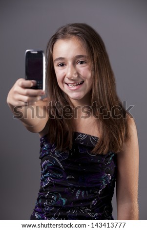 A young teenager taking a self-portrait with her camera phone.