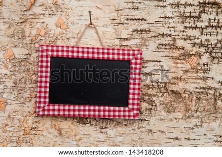 Blank blackboard with checkered frame on wooden background