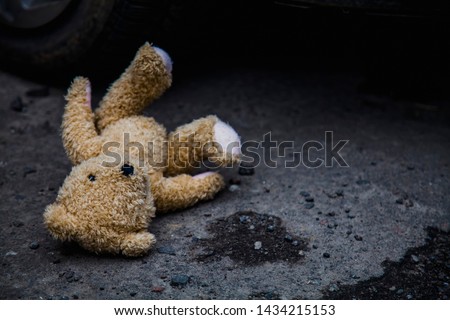 Concept: lost childhood, loneliness, pain and depression. Teddy bear lying down outdoors.
