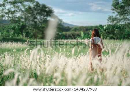 Girl walking on grass field (meadow) in sunny day