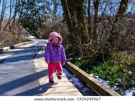 20 months old baby enjoying the nice weather outside. Toddler girl portraits in natural light. Little girl pictures in nature, in Winter. Snow in back. Deer Lake, Coquitlam, British Columbia, Canada
