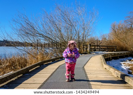 20 months old baby enjoying the nice weather outside. Toddler girl portraits in natural light. Little girl pictures in nature, in Winter. Snow in back. Deer Lake, Coquitlam, British Columbia, Canada