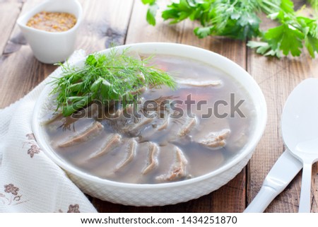Jellied pork tongue in white bowl on a wooden table, horizontal