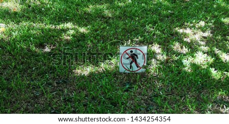 A shot of a no walking through the lawn sign place on the green grass with some sunlight and shadow on it. Backgrounds / textures.
