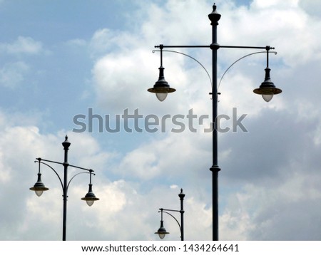 vintage style isolated street lights under blue sky and white clouds in low level perspective. abstract view. painted metal objects.