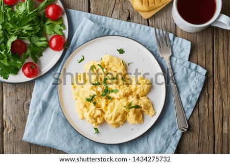 Scrambled eggs, omelette, top view. Breakfast with pan-fried eggs, cup of tea, tomatoes on the old rustic wooden table