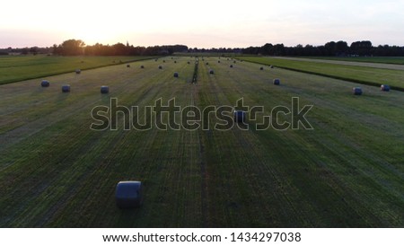 Aerial bird view sundown photo of plastic wrapped fodder bales of dried grass used as animal food to feed domesticated livestock during winter time mostly harvested in spring and summer