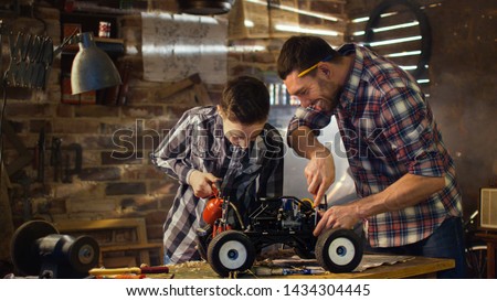 Father and son are working on a radio control toy car in a garage at home. Royalty-Free Stock Photo #1434304445