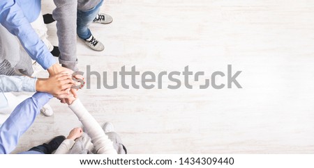 Teambuilding and unity. United millennials standing with their hands together, celebrating victory, top view, panorama, copy space Royalty-Free Stock Photo #1434309440