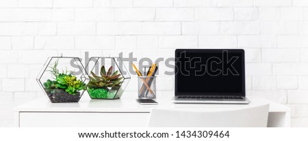 Modern home working place with laptop, and house plants at white brick wall background, copy space, panorama