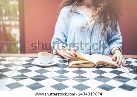 Woman hands book, coffee on wooden table. Toned picture
