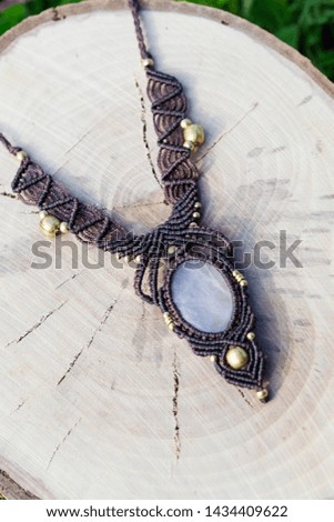Macrame necklace with natural mineral gemstone on wooden background