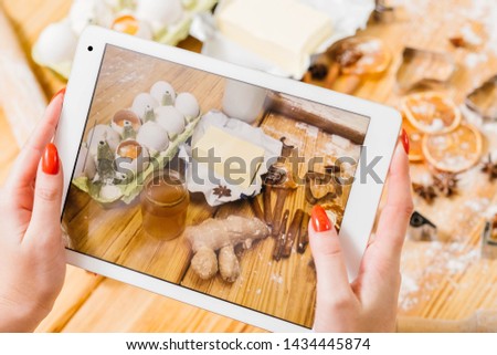 Gingerbread biscuit recipe. Lady using tablet to take picture of pastry ingredients.