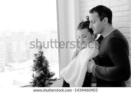Young couple at the window in the apartment black and white

