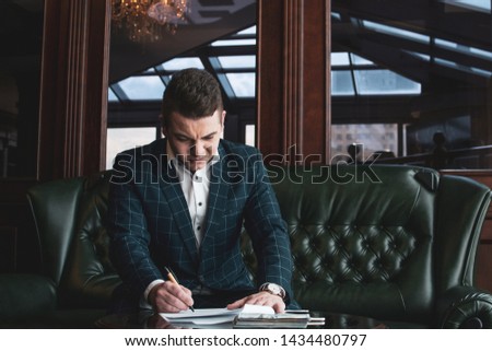 Businessman in suit with documents on table, in the rich office. signs documents