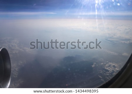 Airplane window overlooking the beautiful clouds and the earth. Sunset in flight on vacation. 