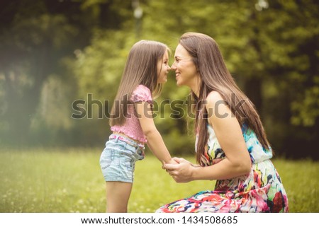 Eskimo kiss. Mother and daughter in nature.