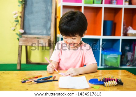 Happy  boy Drawing Picture at School  while sitting at tablel, student, classroom, workshop.