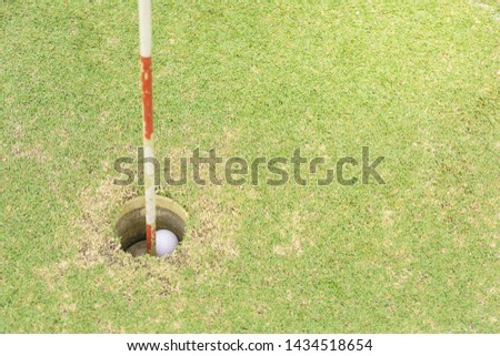 Golf ball on the lawn in the hole green golf pro player putting golf ball into hole , hand , flag in hole and Golf car 