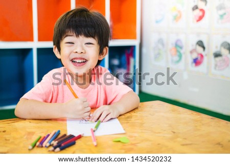 Happy Child boy Drawing Picture at School  while sitting at tablel, student, classroom.