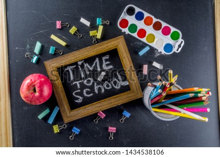 School education supplies on black chalkboard backdrop. Back to school concept. Top view flat lay with copy space for your text