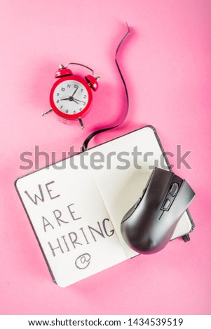 Creative top view flat lay  with we are hiring text on notepad with copy space, bright minimal style. With alarm clock. Concept of new job hiring recruitment process, screening of new team members. 