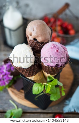Assorted three types of ice cream in a waffle cone. Chocolate, berry and vanilla ice cream. A refreshing summer dessert. Vertical photo. Selective focus.