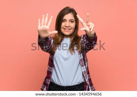 Young girl over pink wall counting eight with fingers