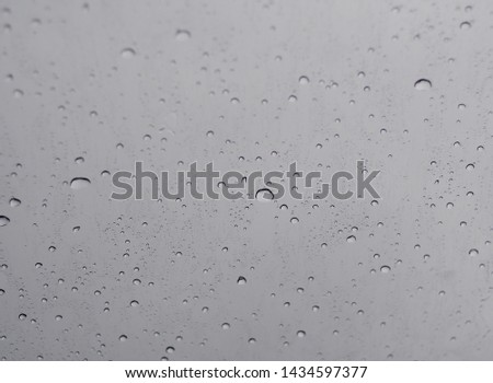 rain drops on car windshield smooth surface reflecting sunlight during rain view from inside a car selective focus blur dull sky background 