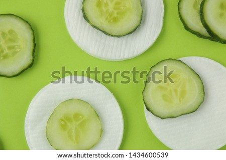 slices of fresh cucumber and cotton sponge on a bright green background. cucumber cosmetics concept. skin care. tonic cucumber extract