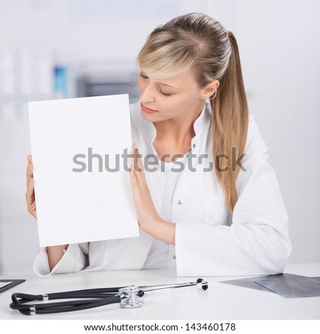 Medical doctor shows white blank paper with stethoscope on the table